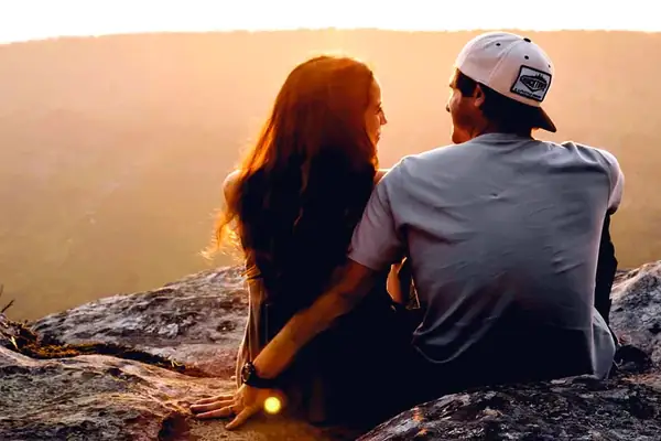 Una pareja mirando el atardecer desde una roca