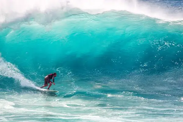 Surfista cogiendo una ola de agua turquesa