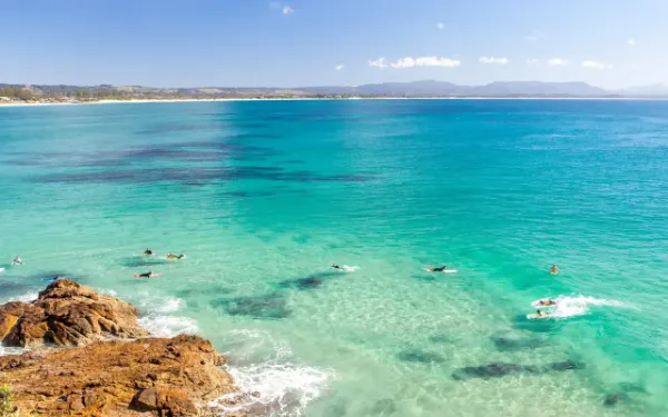 Agua turquesa y surfistas en Wategos, junto al cabo de Byron Bay
