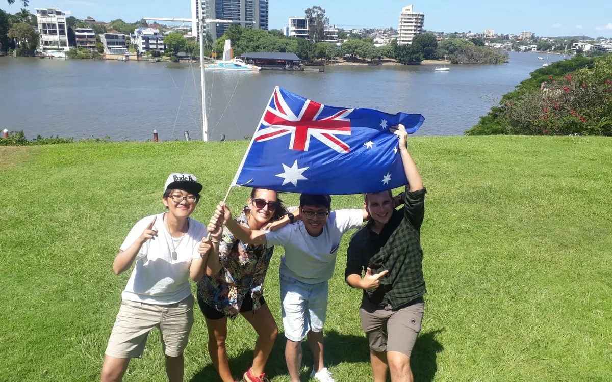 Grupo de amigos con la bandera de Australia junto al río en Brisbane