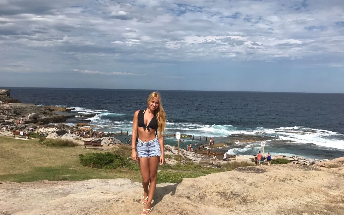 Estudiante en las rocas de la costa de Sydney, con el mar al fondo