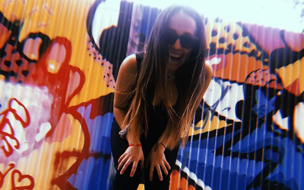 Estudiante riendo delante de un grafiti de colores en una laneway de Melbourne