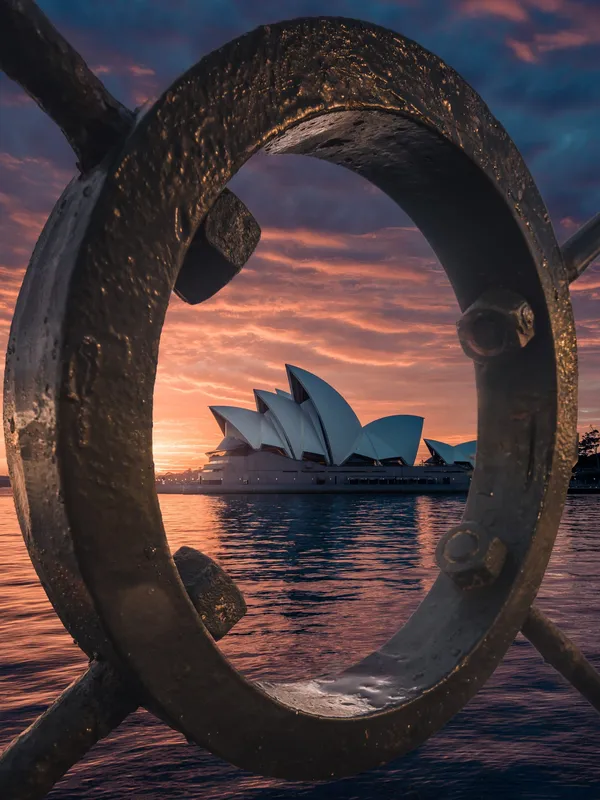 La Ópera de Sydney al atardecer, vista a través de una escultura del puerto
