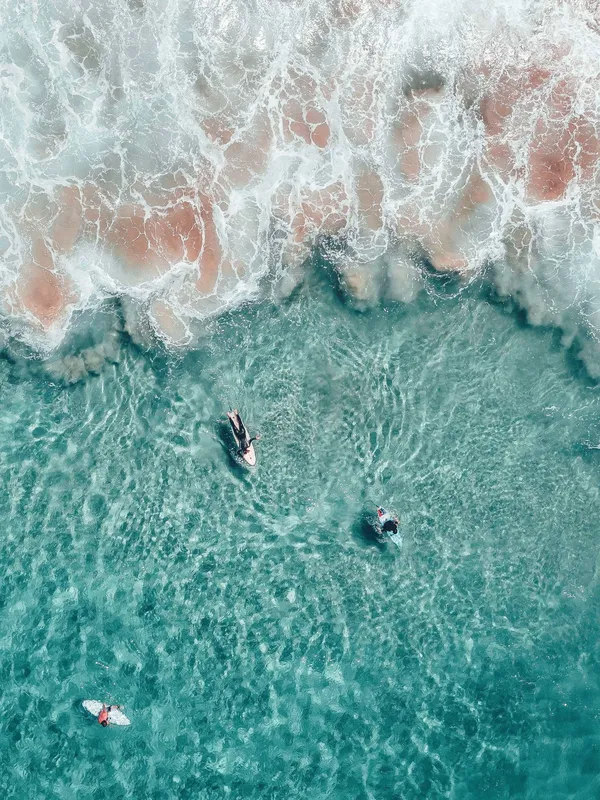 Surfistas en el agua turquesa, vistos desde el aire