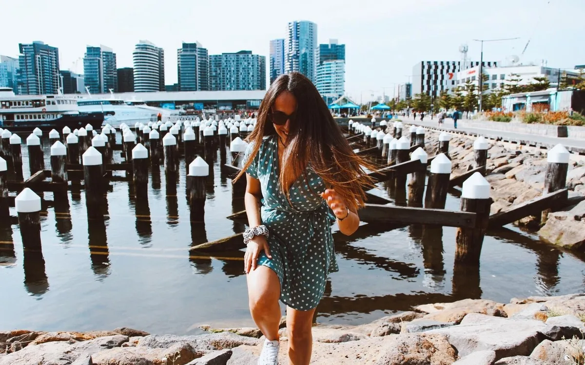 Estudiante en el paseo de Docklands, en Melbourne, con los edificios nuevos del barrio al fondo