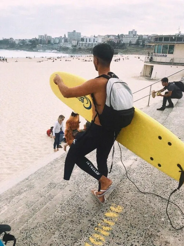 Estudiante con una tabla de surf en Bondi