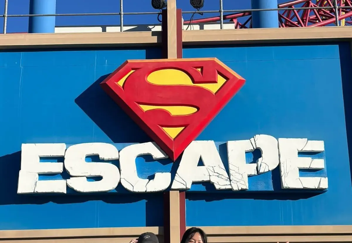 Dos estudiantes en Movie World, junto a la montaña rusa Superman Escape