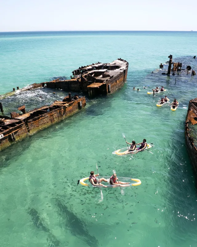 Estudiantes haciendo snorkel junto a un barco hundido en Tangalooma