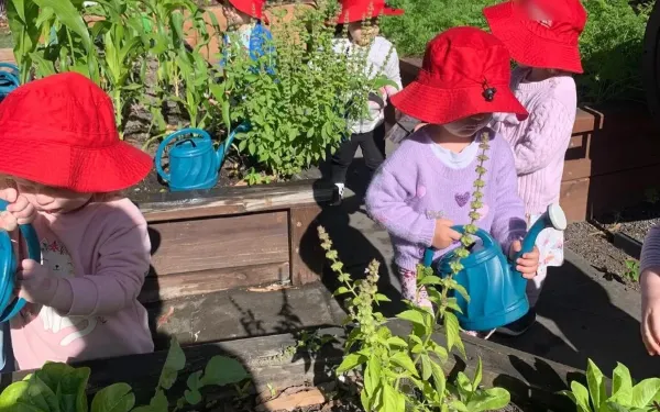 Niños con gorro rojo regando el huerto de una escuela infantil de Gold Coast