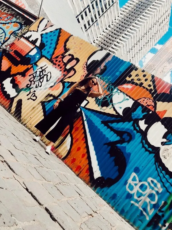 Estudiante posando junto a un mural de colores en un callejón de Melbourne