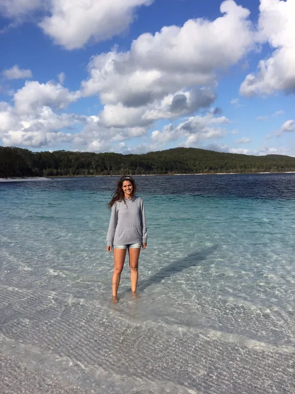 Estudiante de pie en el agua cristalina de una playa de Australia