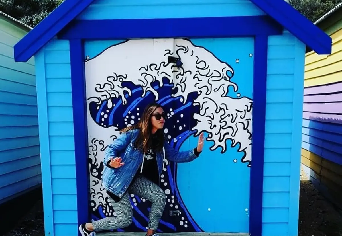 Una estudiante de Salta delante de una caseta de colores de Brighton Beach