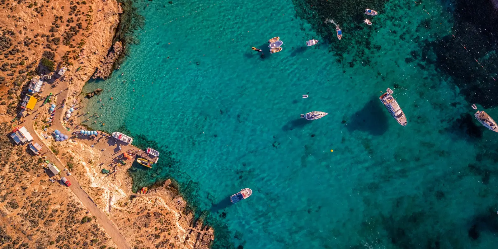 Barcos sobre el agua turquesa de una cala de Malta vista desde el aire