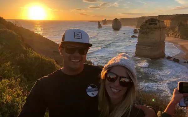 Pareja de estudiantes al atardecer frente a los Doce Apóstoles, en la Great Ocean Road