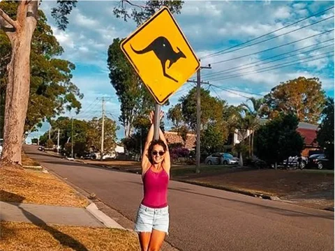 María, estudiante de Salta, colgada de una señal de canguros en Port Stephens