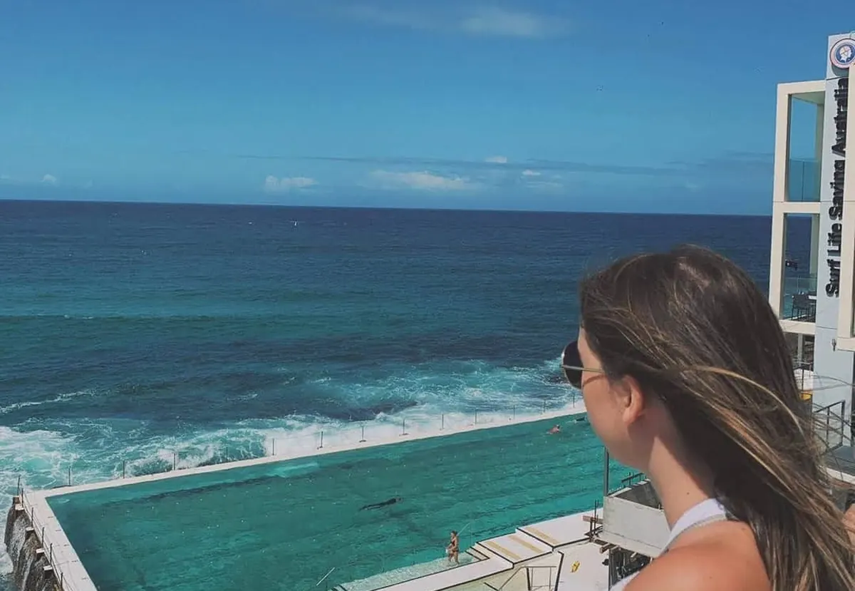 Una estudiante mirando la piscina de Bondi Icebergs sobre el mar