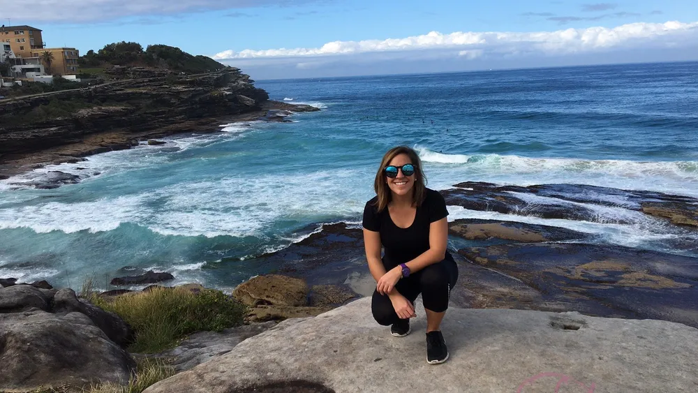 Estudiante de Salta sonriendo en las rocas junto al mar en Sydney
