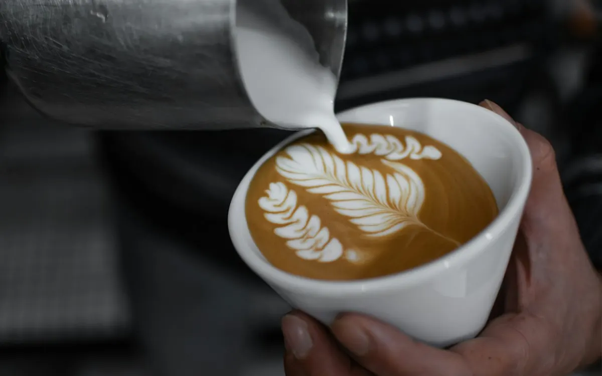 Barista dibujando un corazón con la leche en un café