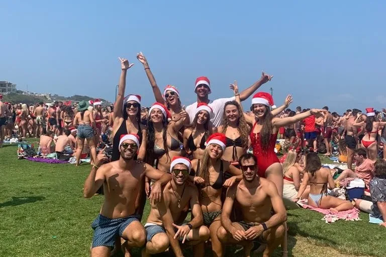 Estudiantes celebrando la Navidad en la playa con gorros de Papá Noel en Australia
