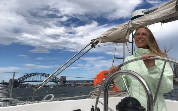 Estudiante de Salta al timón de un velero en la bahía de Sydney, con el Harbour Bridge al fondo