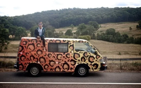 Estudiante de Salta sentada sobre una furgoneta pintada de leopardo en un road trip por Australia